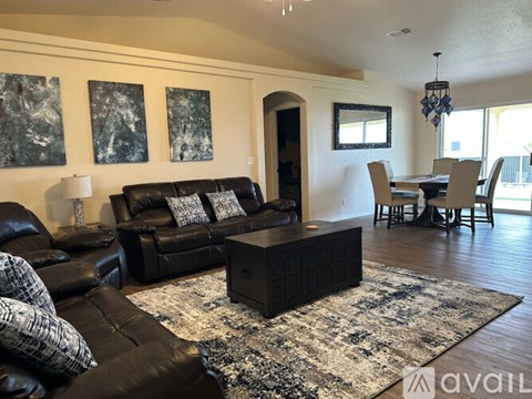 A living room with a black leather couch and a coffee table.