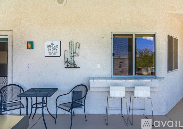 A patio with a table and chairs and a sign that says "No Lifeguard On Duty".