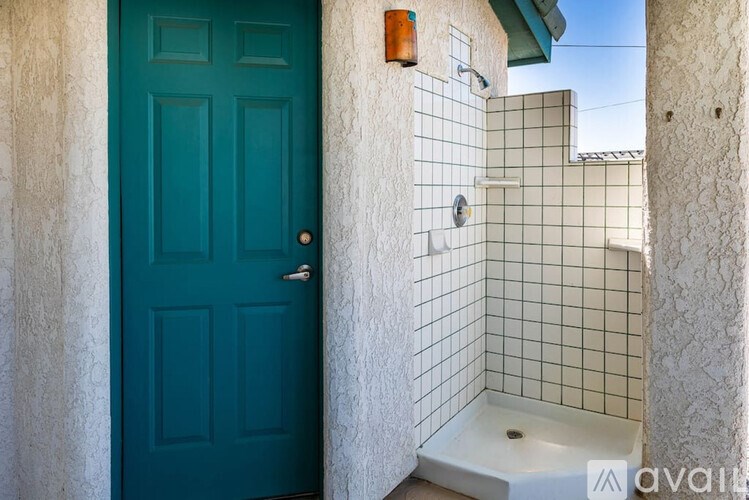A blue door is on the left and a white tiled shower is on the right.