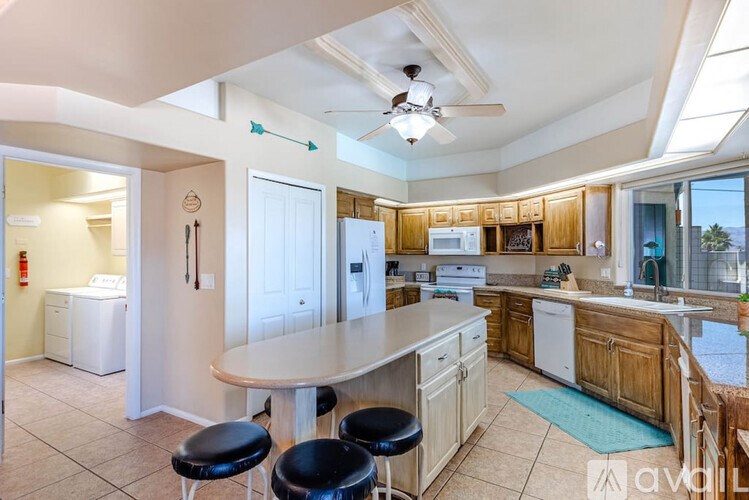 A kitchen with a white ceiling and a large island with four black stools.