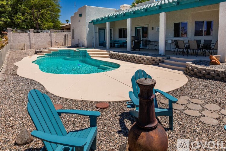 A blue chair sits next to a pool in a backyard.