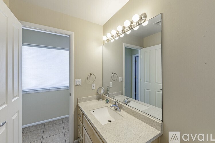 A bathroom with a vanity, mirror, and lights.