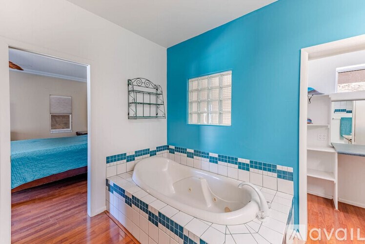 A blue bathroom with a white tub and wooden floors.
