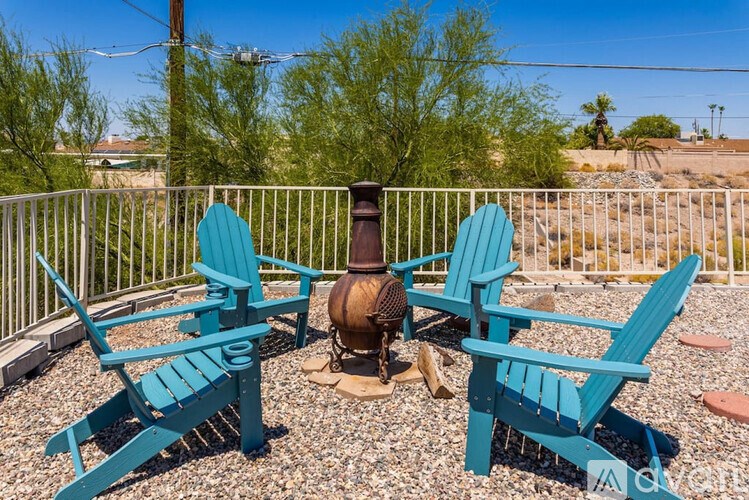 Two blue chairs and a fire pit on a patio.