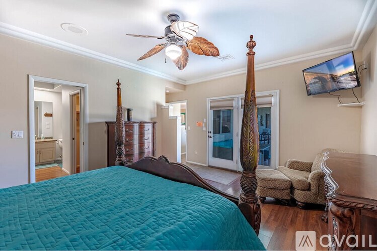 A bedroom with a large bed and a ceiling fan.