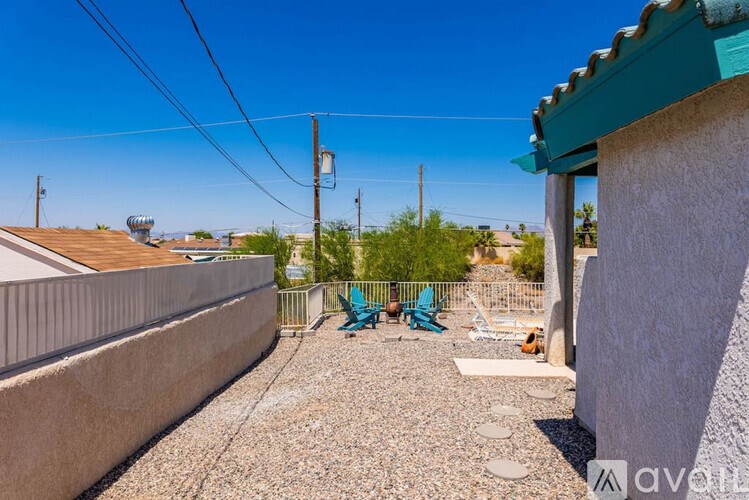 A patio area with a table and chairs is set up on a gravel surface.