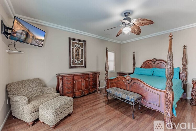 A bedroom with a four poster bed, a chair and a dresser.