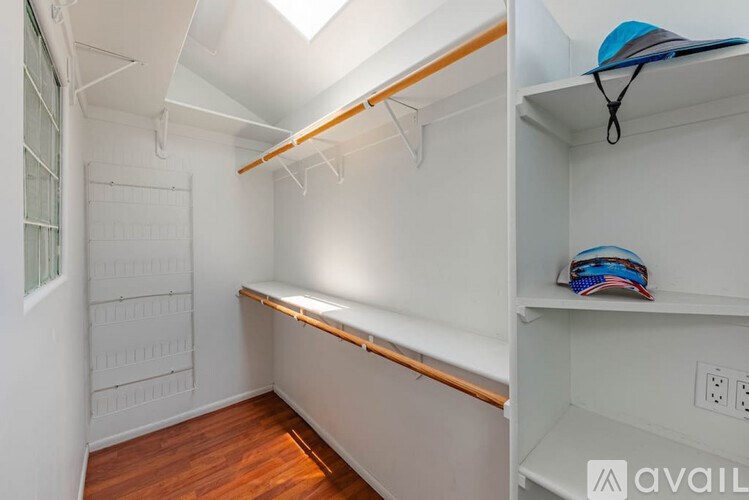 A small, white closet with a skylight and a shelf.