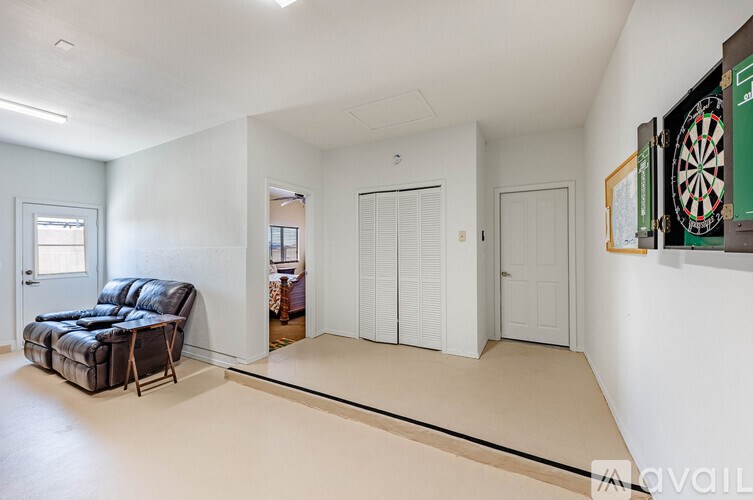 A room with a dartboard on the wall and a black leather chair.