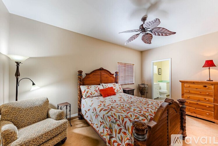 A bedroom with a bed, chair, and ceiling fan.