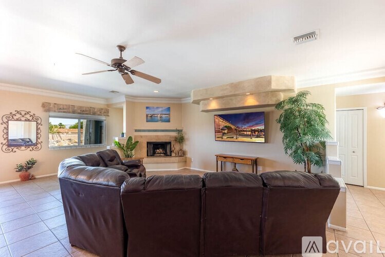 A living room with a brown leather couch and a painting on the wall.