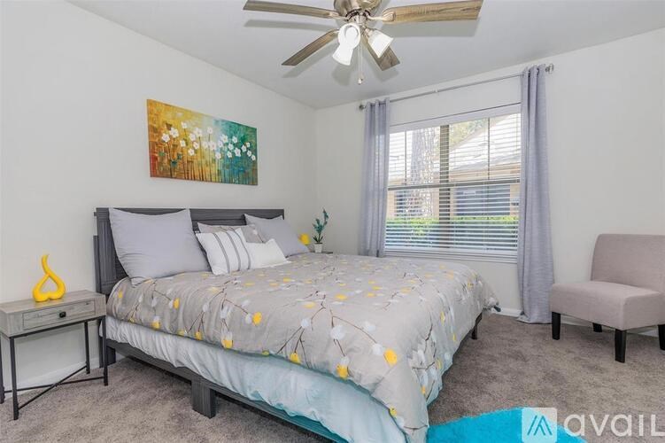 A bedroom with a bed, chair, and painting on the wall.