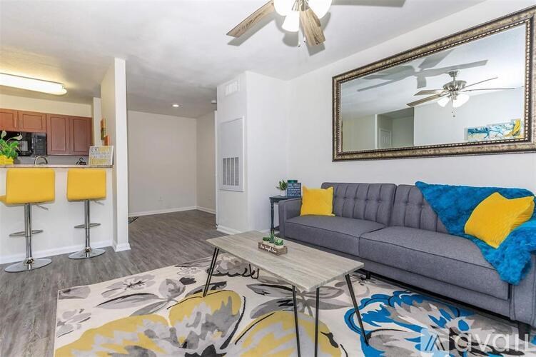 A living room with a grey couch and a large mirror on the wall.