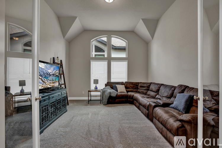 A living room with a brown leather couch and a television.