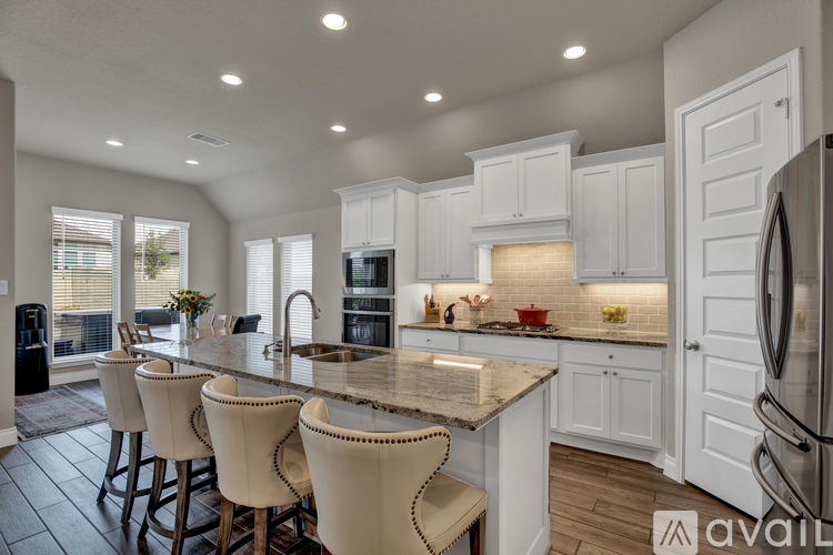 A kitchen with white cabinets and a marble countertop.