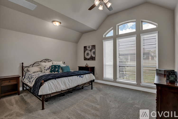 A bedroom with a bed, nightstand, and window with blinds.