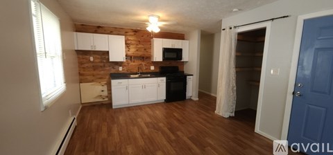 A kitchen with wooden walls and white cabinets.