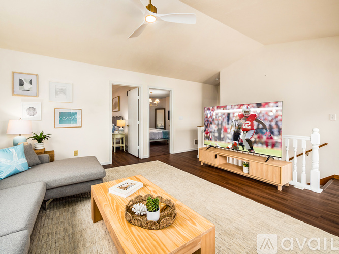 A living room with a grey couch, a wooden coffee table, and a television.