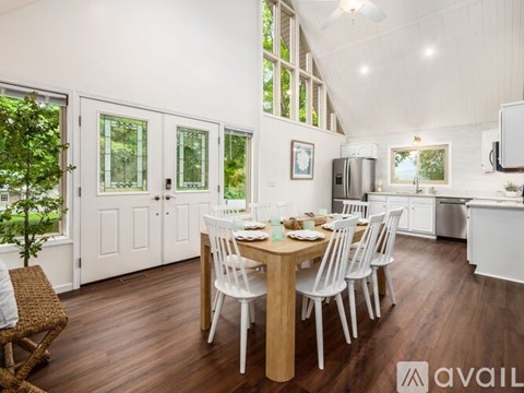 A dining room with a wooden table and white chairs.