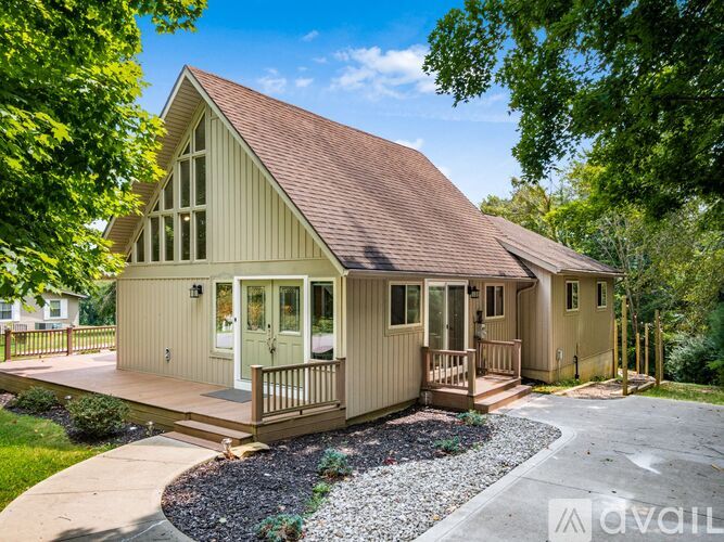 A house with a brown roof and a porch surrounded by trees.