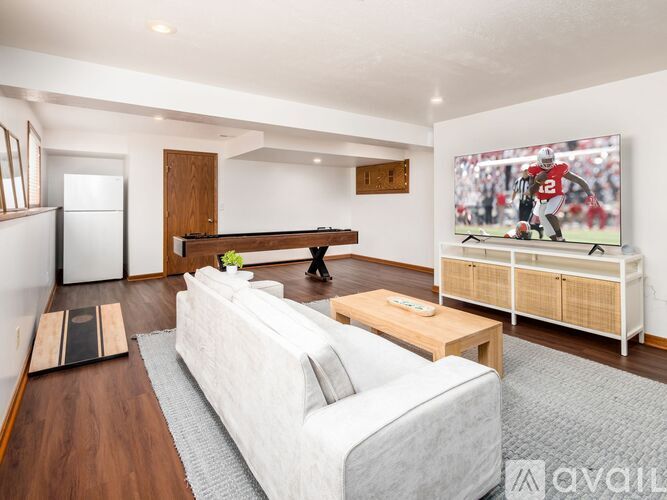 A living room with a white couch and a television showing a football game.