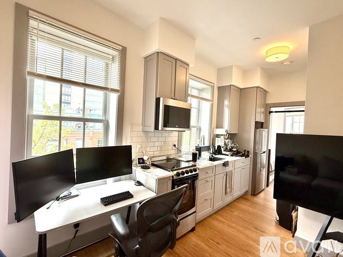 A modern kitchen with a desk and chairs in the foreground.