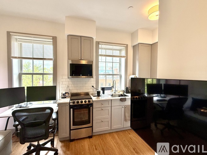A modern kitchen with a black chair and wooden floors.