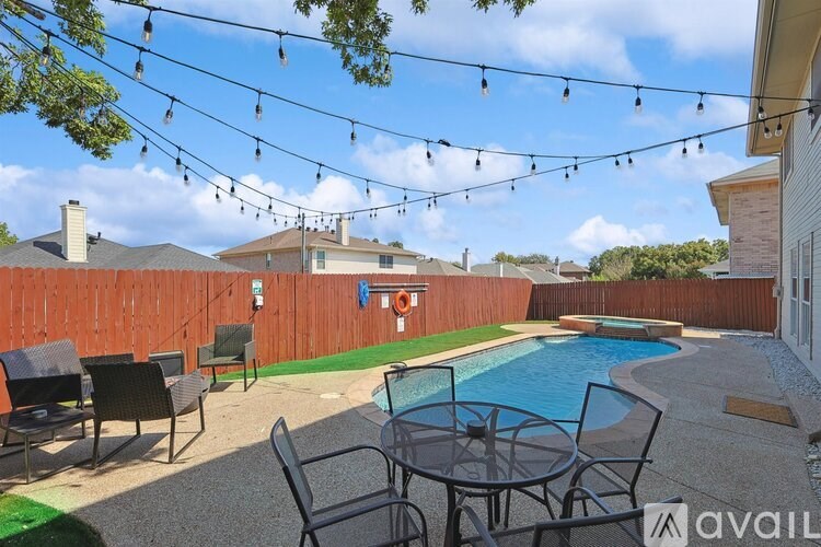 A backyard with a pool and patio furniture.