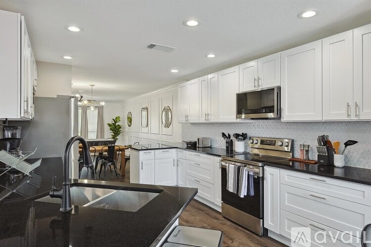 A modern kitchen with white cabinets and black countertops.