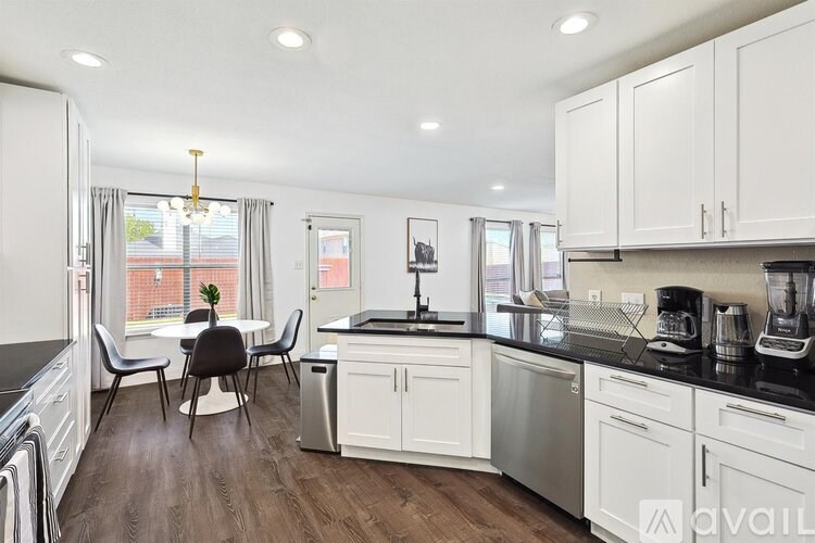 A kitchen with white cabinets and a black countertop.