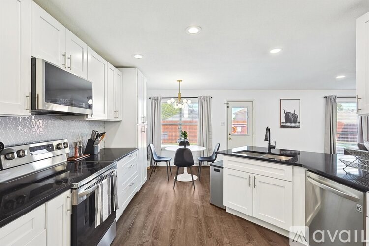 A kitchen with white cabinets and black countertops.