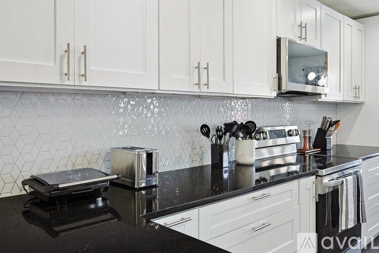 A kitchen with white cabinets and a black countertop.