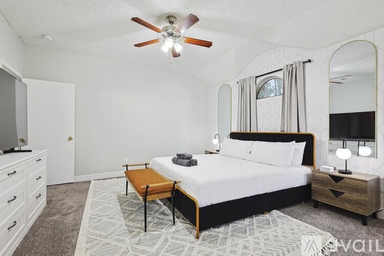 A bedroom with a large bed, a ceiling fan, and a dresser.