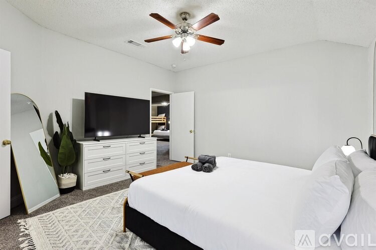 A bedroom with a bed, dresser, and ceiling fan.