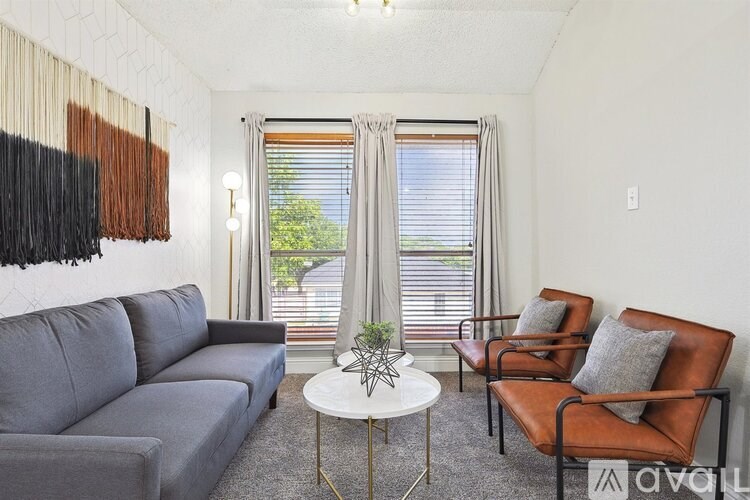 A living room with a grey couch, a white coffee table, and a window with blinds.