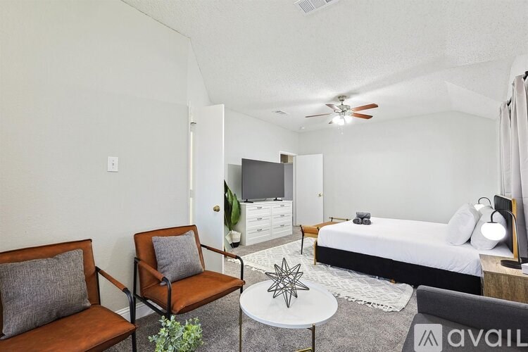 A bedroom with a bed, a chair, a dresser, and a ceiling fan.