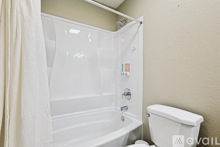 A white bathtub with a shower curtain and a toilet in a bathroom.