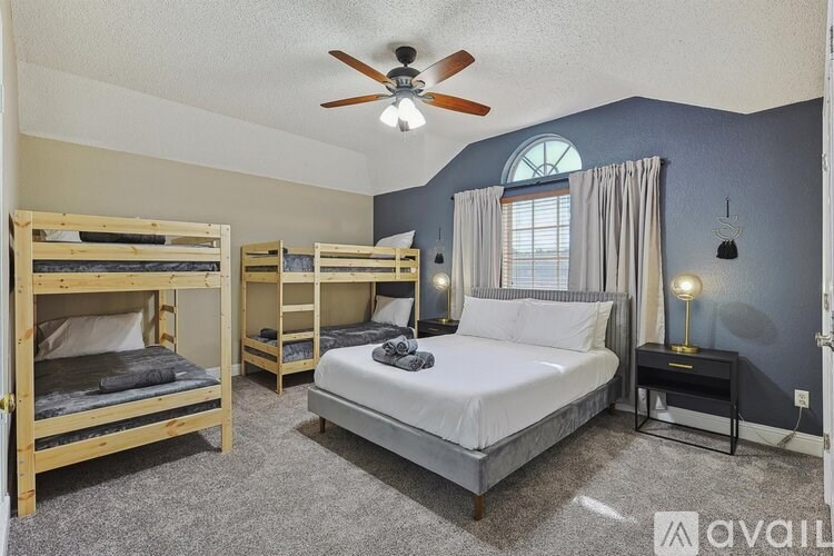 A bedroom with a ceiling fan and a bed with a white comforter.