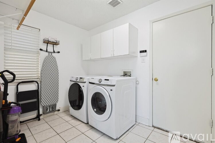 A laundry room with a washer and dryer and a cabinet above the washer.