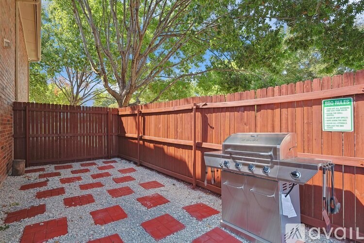 A backyard with a BBQ grill and a checkered pattern on the ground.