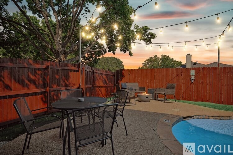A backyard with a table, chairs, and a pool.