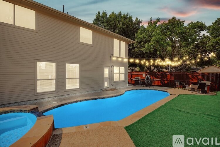 A pool in a backyard with lights strung above it.