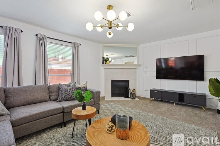 A living room with a grey couch, a wooden coffee table, a fireplace, and a flat screen TV mounted on the wall.