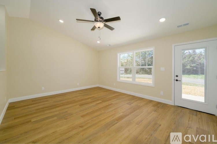 A room with a ceiling fan and wooden flooring.