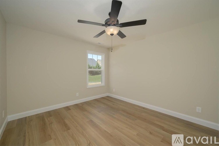 A room with a ceiling fan and wooden flooring.