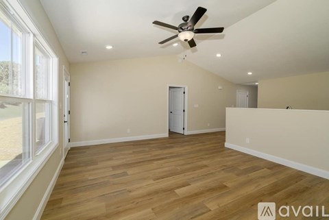 A spacious room with a ceiling fan and wooden flooring.