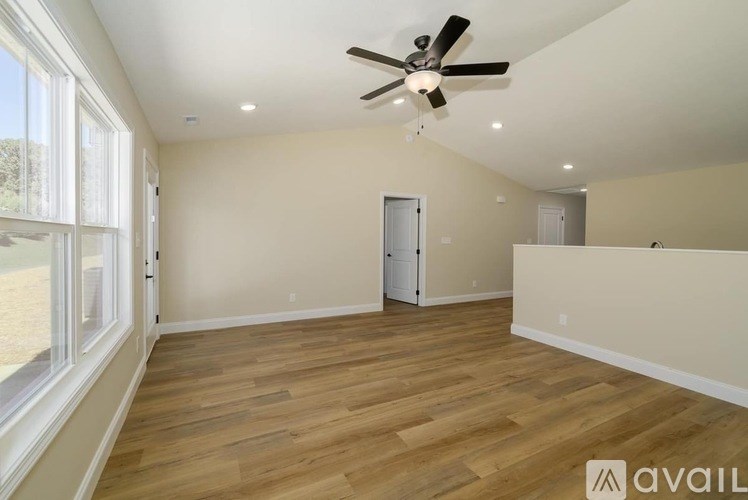 A spacious room with a ceiling fan and wooden flooring.