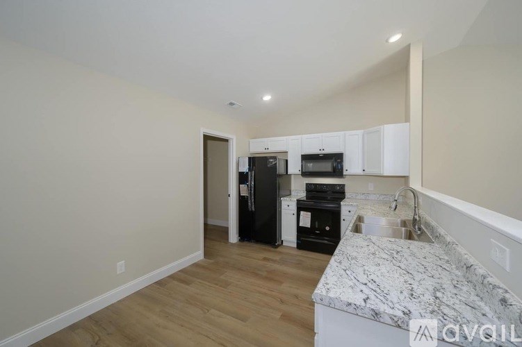 A kitchen with a marble countertop and wooden flooring.