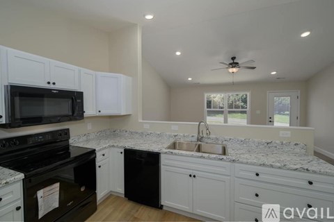 A kitchen with white cabinets and a black stove top oven.