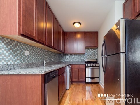 A kitchen with wooden cabinets and a black refrigerator.